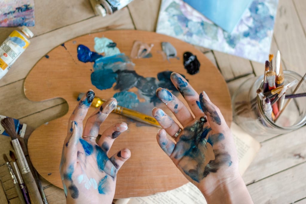 Closeup of female hands mixing paint on a palette at workshop. Artist