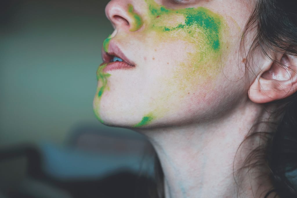 Moody portrait of a young woman with her face painted of green