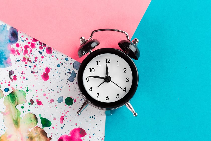 Vintage alarm clock on a creative colorful background with paint sprinkles
